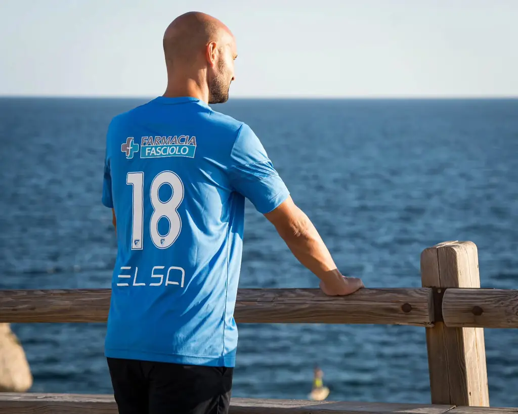 Un giocatore con la maglia azzurra numero 18 guarda il mare